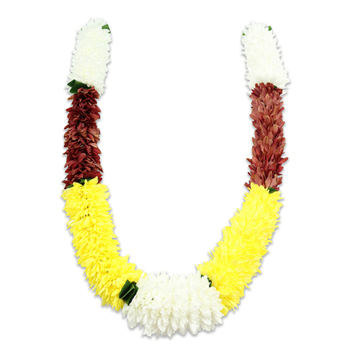 Framed on a pure white field that throws every detail into relief, this U-shaped floral garland reads as a study in colour, texture and ritual. Constructed from artificial fabric petals, it imitates the delicate geometry of real flowers: tight white clusters that recall small chrysanthemums or jasmine, then a narrow band of maroon-reddish blooms with a dense, velvety appearance, followed by an expansive sweep of bright yellow that dominates the lower curve. Where the two yellow arms meet a fuller cluster of white chrysanthemums forms the visual heart of the piece, punctuated by small dark green leaf accents that act as separators and lend a hint of botanical realism. Light falls softly across the garland, revealing the subtle shadow under the U and the depth created by layering thousands of individual petals-each one cut, folded and secured to produce consistent volume and a plush hand. This type of mala is traditionally used for Hindu puja, temple offerings, Indian weddings or Diwali celebrations, and the chosen palette-white for purity, yellow for prosperity, maroon for devotion-retains that symbolic weight. Imagining it in a local context, the garland could be draped above an altar in a home near Eastcote High Road or placed at an entrance for a family celebration close to Ruislip Lido; its durable, artificial construction makes it suitable for repeated ceremonial use while still conveying the reverence and festivity those moments require. The overall impression is one of careful craft: ceremonial, robust and quietly beautiful.