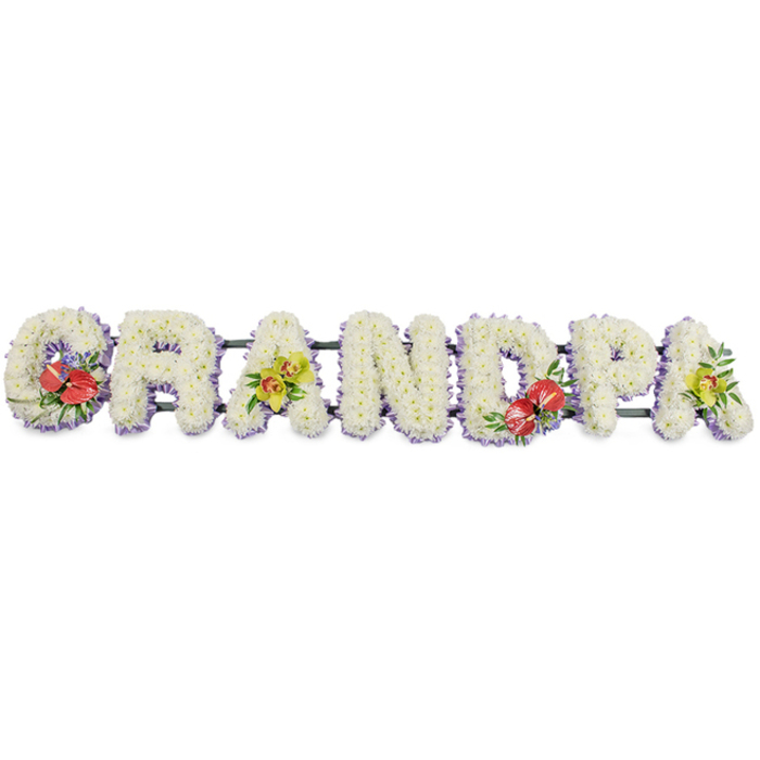 In this detailed GRANDPA floral tribute, each letter is carefully shaped from fresh white chrysanthemums and arranged in a straight, horizontal line, reminiscent of a display placed along the front of a coffin or at the head of a graveside in Eastcote. The letters are tall, blocky, and three-dimensional, completely carpeted in small chrysanthemum heads that sit tightly side by side so no underlying structure is visible through the soft sea of petals. The effect is of a seamless, snowy surface, with the white flowers symbolising purity, remembrance, and peace. Beneath the flowers, a thin band of light lavender ribbon edges each letter, the gentle purple tone just visible at the lower outline, giving a subtle, refined frame to the bright white. The letters are supported by narrow dark green bars which connect them and provide stability but remain unobtrusive, letting the blooms take centre stage. Four accent sprays punctuate the design with rich colour: the 'G' features a striking group of deep red anthuriums, their glossy heart-shaped spathes and pale yellow spadices cradled in dark green foliage and a hint of complementary filler. The first 'A' is softened with yellow-green orchid blooms, their elegant, almost waxy petals and buds surrounded by fresh, bright leaves. Near the middle-right, the 'D' repeats the anthurium spray, bringing continuity and a second splash of passionate red. On the far right, the final 'A' mirrors the first 'A' with another cluster of lime-toned orchids and green foliage. The tribute feels both traditional and contemporary, the kind of bespoke grandad arrangement Eastcote Flowers might prepare for a funeral or memorial service, offering a gentle, beautifully crafted expression of love and thanks.