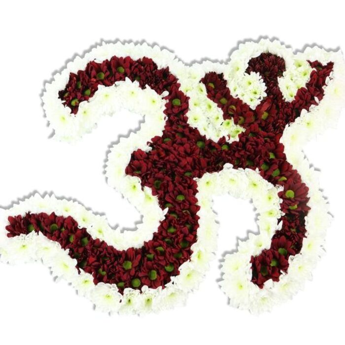 A reverent, hand-constructed Om symbol formed entirely from densely packed small chrysanthemums rests against a stark white background, its sculptural silhouette sharply defined and emotionally resonant. The central mass is a rich, deep red to maroon composed of hundreds of tiny pompon-like flowers, each with a small lime-green center that gives the red surface an animated, natural flecking and subtle contrast. Encircling that red core is a generous, undulating border of pure white spray chrysanthemums that trace the symbol's curves and internal negative spaces, the white petals catching light to create a luminous outline and making the sacred letter read with immediate clarity. The overall texture is lush and tactile - a soft, cloud-like density of petals that still holds crisp, intentional shape - while a faint shadow under the piece suggests it sits slightly raised, a bespoke floral reliquary rather than a flat print. The arrangement carries the quiet scent of fresh blooms, gentle and grounding, appropriate for meditation altars, temple decorations, or sympathy displays. As a local florist I imagine it delivered with care to community halls on Eastcote High Street or positioned near the quieter corners of Hillingdon meeting spaces for services and cultural observances. Crafted by experienced hands, this design - available through Eastcote Flowers for careful local placement - balances artistic precision with devotional warmth, suitable for spiritual ceremonies, yoga events, or commemorative services in and around the district.