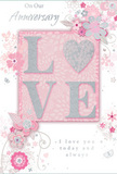 This beautifully detailed anniversary card feels like a romantic keepsake you could imagine tucked alongside a bouquet delivered to a doorstep in Eastcote. The background is a gentle, pastel pink, smoothly blended with no harsh edges, creating a calm, cloudlike canvas. In the centre, the word LOVE appears in large, slightly raised letters that give a subtle three-dimensional effect. Each letter is edged and dusted with shimmering silver glitter, luminous but controlled, catching light the way fine glass vases gleam in a florist's window along Field End Road. The letters appear soft to the eye yet tactile, inviting a slow, appreciative touch. Flowing from the sides and corners of this word is a graceful spray of illustrated flowers and leafy tendrils. The blossoms are rendered in blush, mauve, and ivory tones, with fine outlines and gentle shading that recall delicate ink and watercolour work. The petals seem to open toward the central word, while slender vines curl and loop in airy arcs, giving the card a sense of lightness and movement. Occasional silver accents-perhaps tiny leaves, dots, or softly drawn butterflies-add depth and a whisper of sparkle, like the last glints of light on an evening Eastcote street. An anniversary message, including phrases such as On Our Anniversary and I love you today and always, is written in elegant script, its flowing lines echoing the curves of the illustrated vines. Altogether, the card suggests tenderness, commitment, and quiet celebration, visually capturing the essence of a long, shared journey in a beautifully arranged, floral-inspired design.